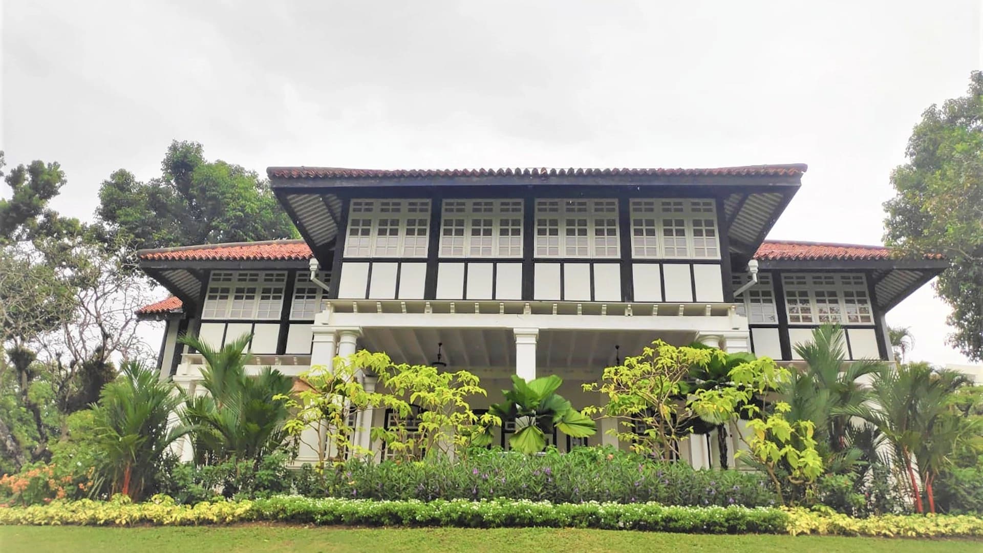 Colonial clubhouse behind a mown lawn and layered shrub planting at The Pyramid Club